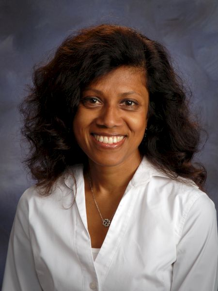 A smiling woman with shoulder-length dark hair wearing a white blouse, posing for a professional portrait.